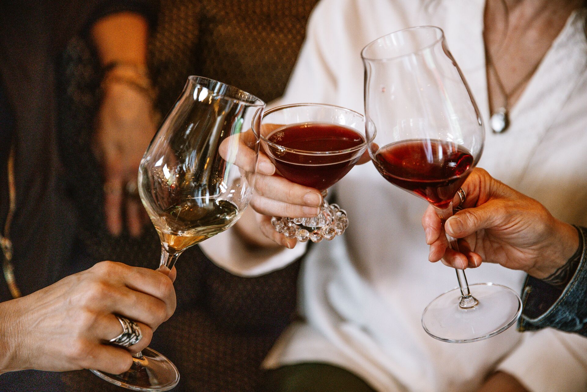 Three friends toasting with glasses of red and white wine